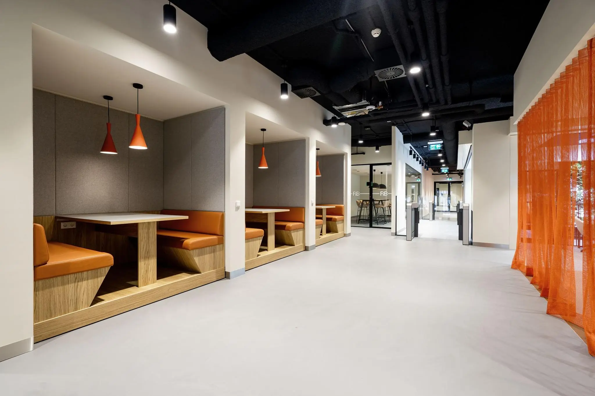 Moderne kantoorruimte aan de Aert van Nesstraat met houten zitnissen, oranje accenten en strakke industriële afwerking.